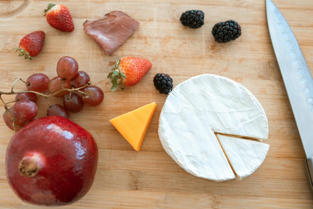 A gourmet arrangement of cheeses and fruits on a wooden board, perfect for a stylish spread.